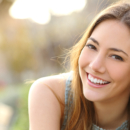 Woman smiling with perfect smile and white teeth in a park and looking at camera